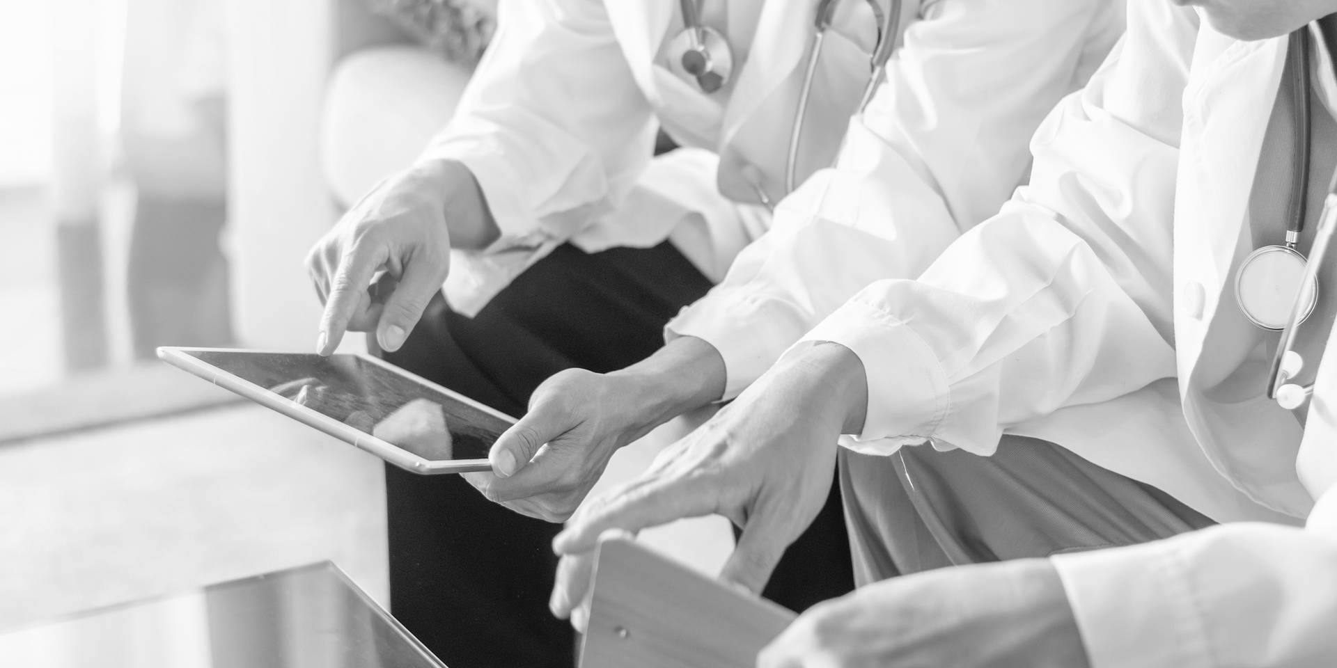 Two doctors sitting and looking at an iPad screen together