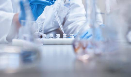 Lab technician conducting testing with vials and dropper
